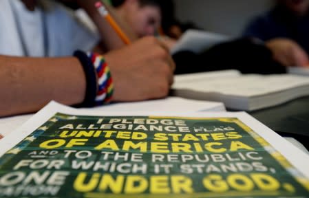 A copy of the Pledge of Allegiance rests next to an immigrant in a writing class the U.S. government's government's newest holding center for migrant children in Carrizo Springs