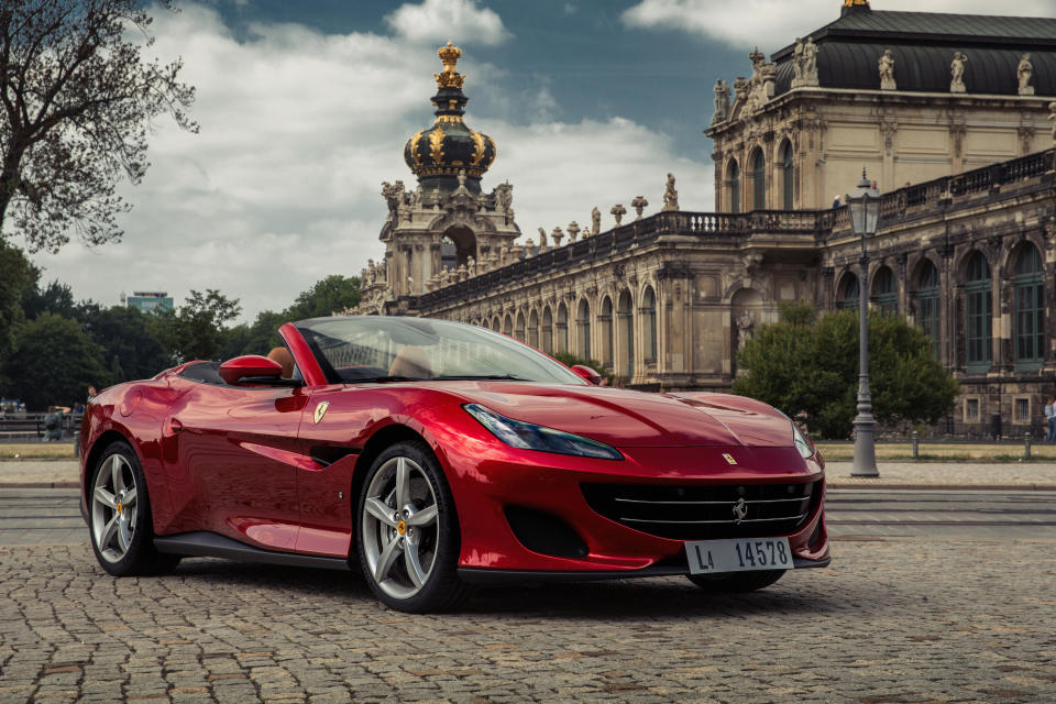 A metallic red Ferrari Portofino, a convertible luxury sports car, shown with the top down.