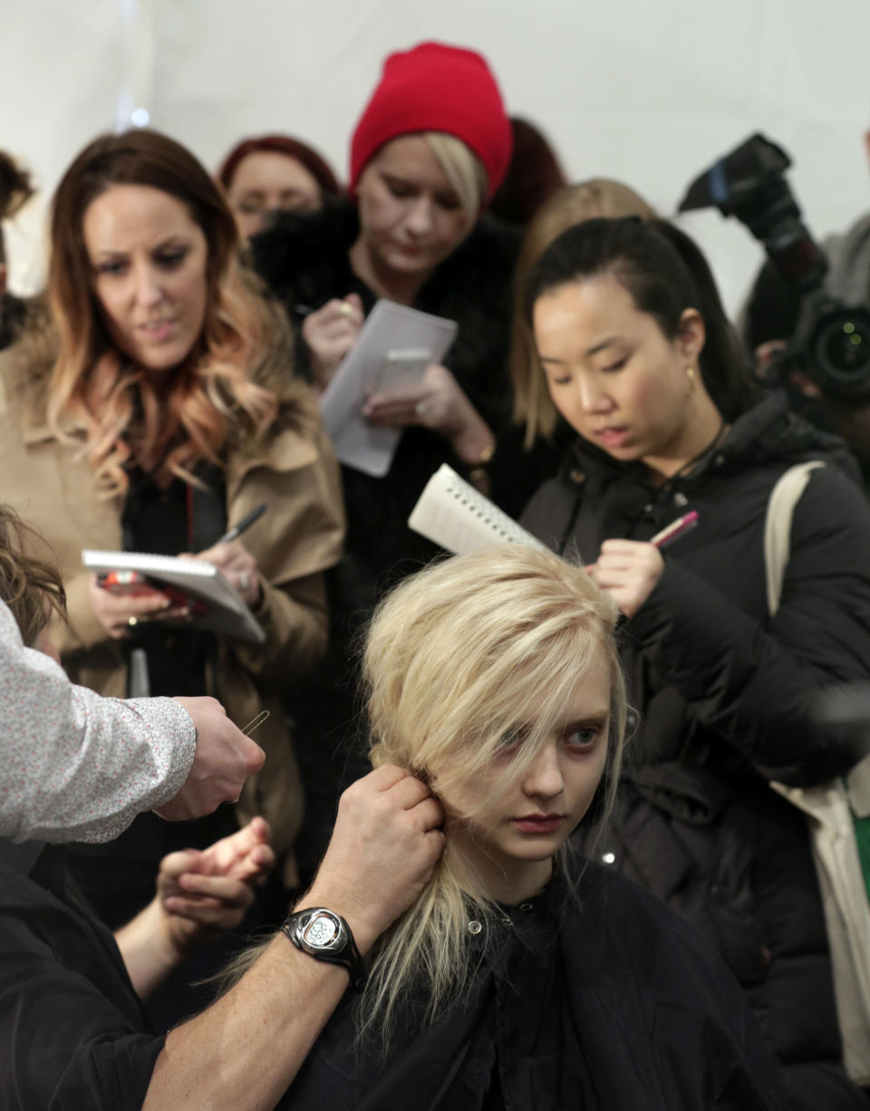 Fashion journalists take notes backstage as a model's hair is styled before the Tadashi Shoji Fall 2013 collection is modeled during Fashion Week in New York, Thursday, Feb. 7, 2013. (AP Photo/Richard Drew)