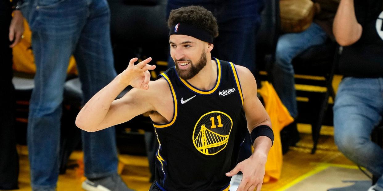 Klay Thompson smiles and holds up three fingers after hitting a three-pointer.