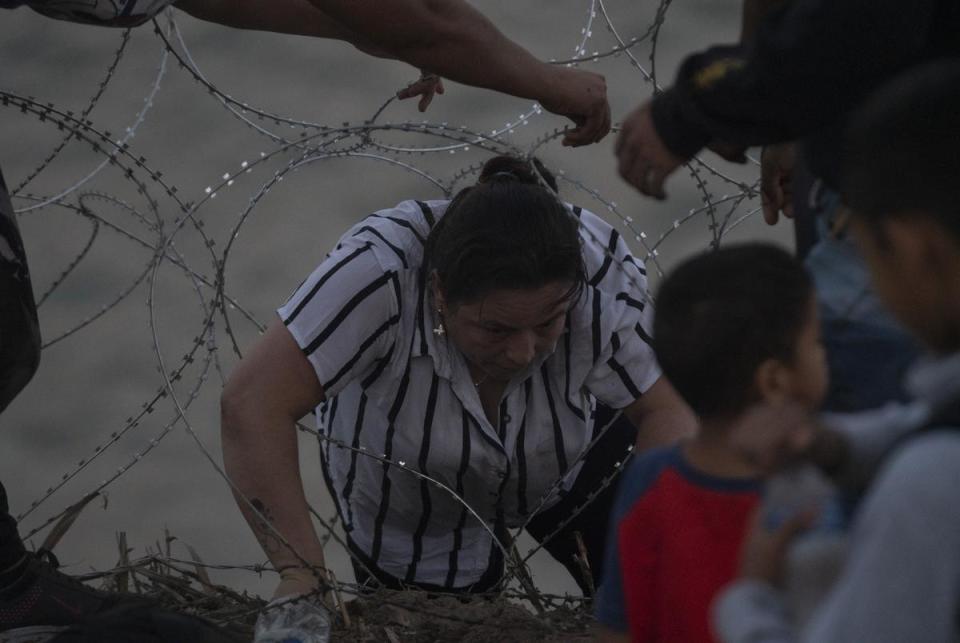 A Colombian mother goes through concertina wire to turn herself in with her daughter and other people in Eagle Pass, Texas on July 29, 2023. As there is concertina wire installed along the Urbina’s property, migrants are told to walk to the end of the property, taking them approximately an hour from that point. Many make that walk which can be difficult to do through slippery rocks in the water, the current and the inclined river bank, while some find spots through the concertina wire and manage to get through.
Verónica G. Cárdenas for The Texas Tribune