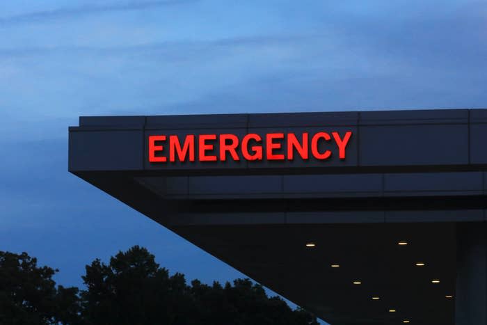 Sign for the emergency entrance of a hospital building, with trees visible in the background