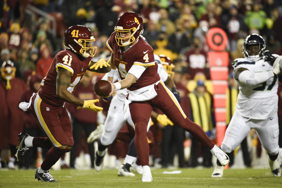 Washington Football Team quarterback Taylor Heinicke (4) hands the ball off to running back J.D. McKissic (41) during the first half of an NFL football game against the Seattle Seahawks, Monday, Nov. 29, 2021, in Landover, Md. (AP Photo/Mark Tenally)