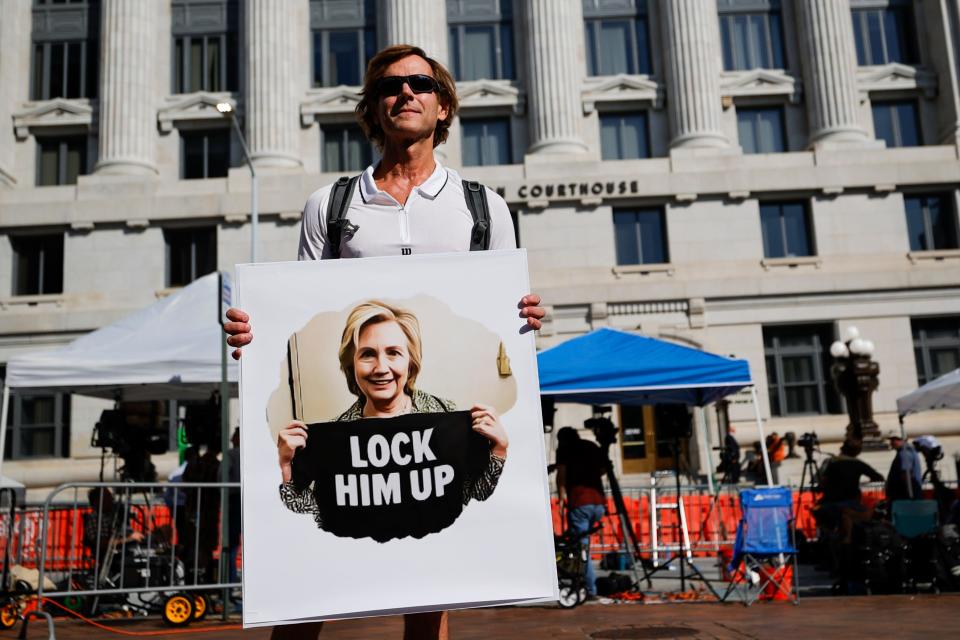 A demonstrator holding a sign that reads "Lock Him Up" stands outside the federal courthouse in Atlanta, Ga., on Aug. 14, 2023.