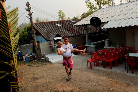 Gorsak Kong Tawan, 13, is carried by a relative after using the toilet at their home in Mae Hong Son, Thailand, April 3, 2018. Boys who participate in an annual Poy Sang Long celebration, a traditional rite of passage for boys to be initiated as Buddhist novices, are not allowed to touch the ground or walk by themselves until the festival has ended. REUTERS/Jorge Silva