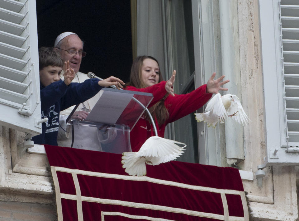 Pope Francis looks at two children as they free doves during the Angelus prayer he celebrated from the window of his studio overlooking St. Peter's Square, at the Vatican, Sunday, Jan. 26, 2014. Pope Francis has called for "constructive dialogue" between Ukraine's authorities and its people, urging all to renounce violence in the upheaval convulsing their country. Speaking from a window of the Apostolic Palace in the Vatican to thousands of faithful in St. Peter's Square, Francis said he was praying for Ukraine, especially for those who have lost their lives in recent days. He appealed on Sunday for "the spirit of peace and the search for the common good" to prevail in the eastern European nation. (AP Photo/Gregorio Borgia)