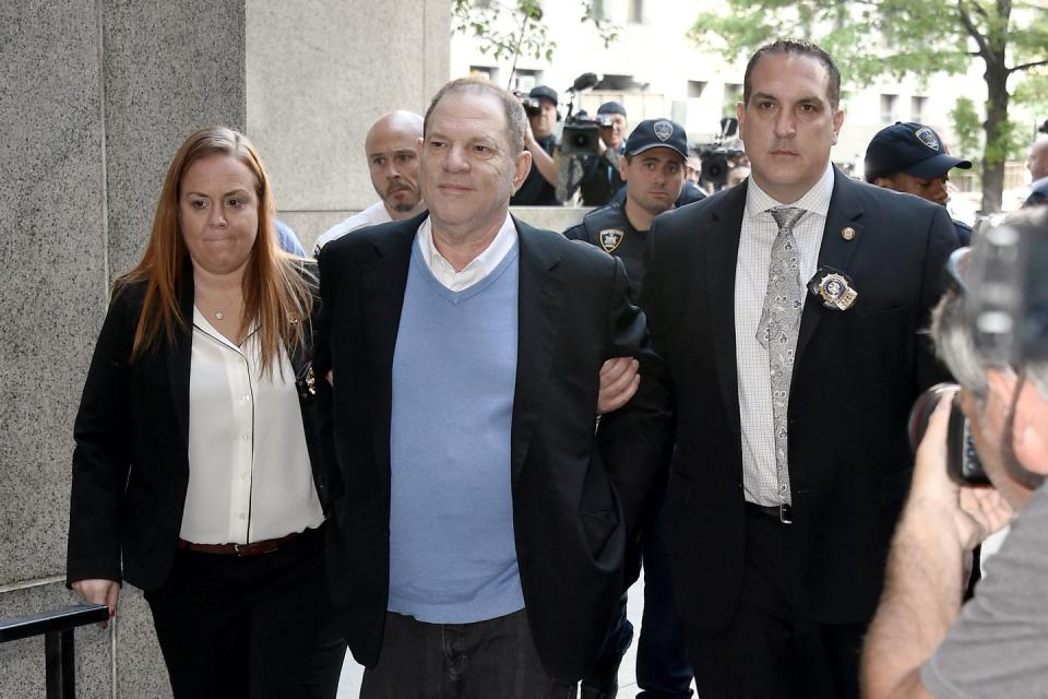 harvey weinstein arriving in court for an arraignment with his arms interlocked with two officials