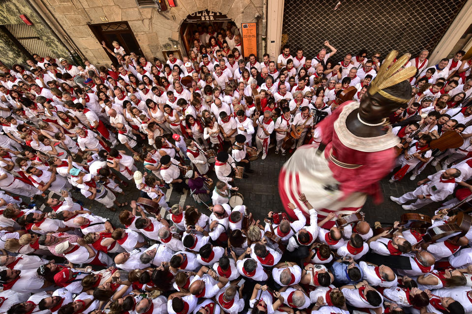 A giant member of San Fermin Comparse Parade takes part in a procession surrounded by people dressed in white and red clothes at the San Fermin Festival in Pamplona, northern Spain, July 7, 2019. (Photo: Alvaro Barrientos/AP)