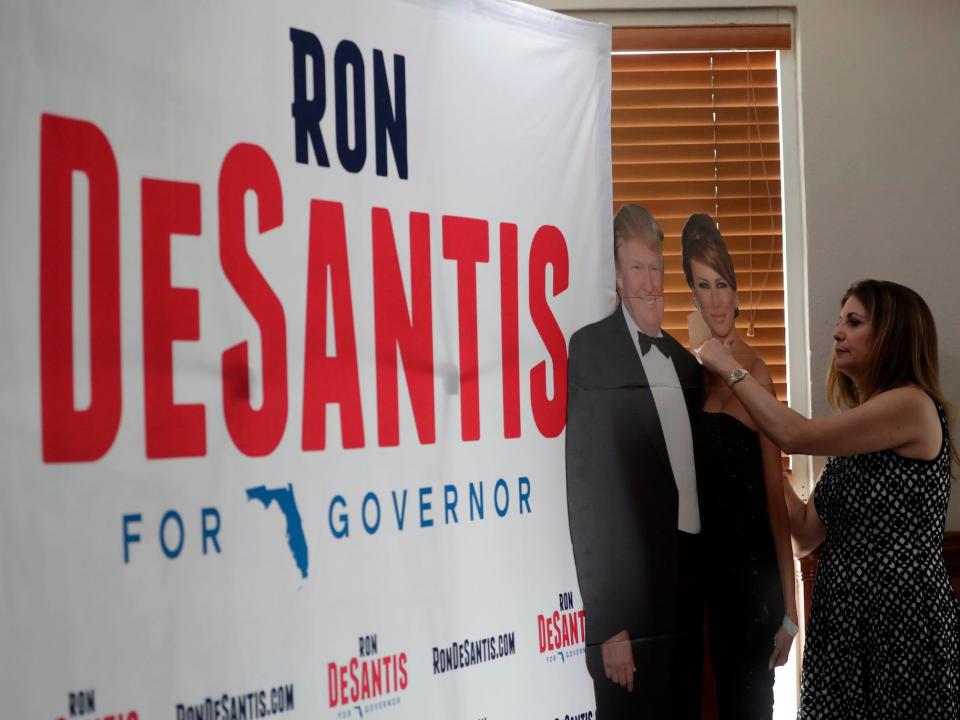 Maricel Cobitz, with the Federation of Republican Women, adjusts a cutout of President Donald Trump and first lady Melania Trump before a campaign appearance by Republican gubernatorial candidate Ron DeSantis at Versailles restaurant, Monday, Aug. 27, 2018, in Miami. Trump is endorsing DeSantis in the election.