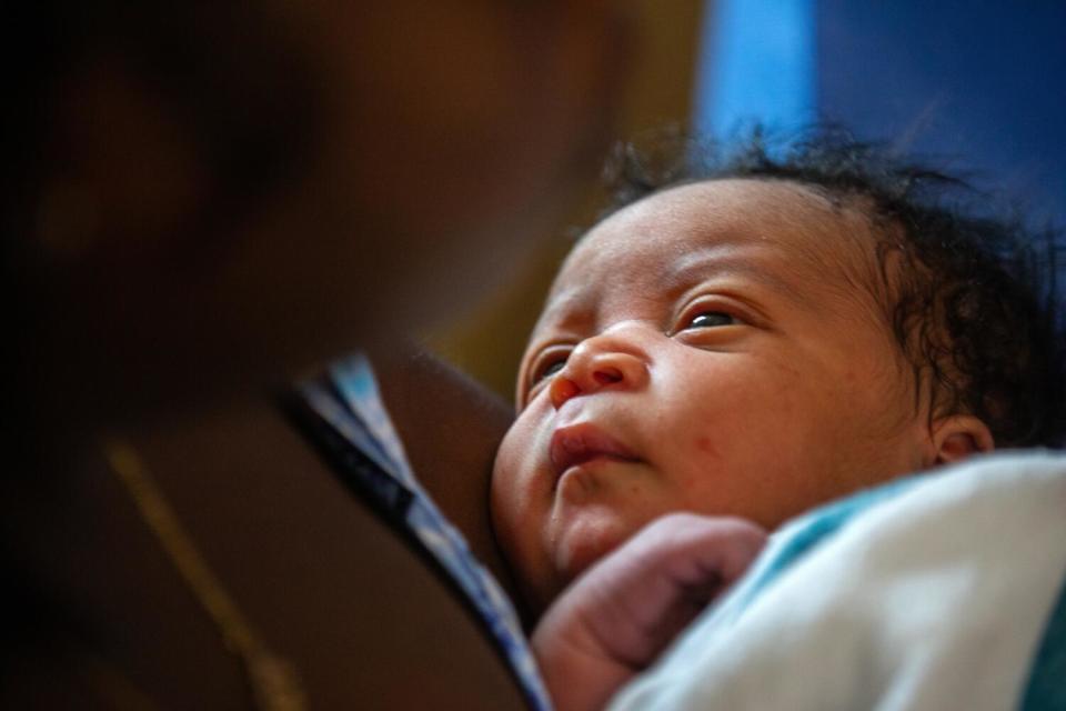 A woman looks down at a baby she's holding.