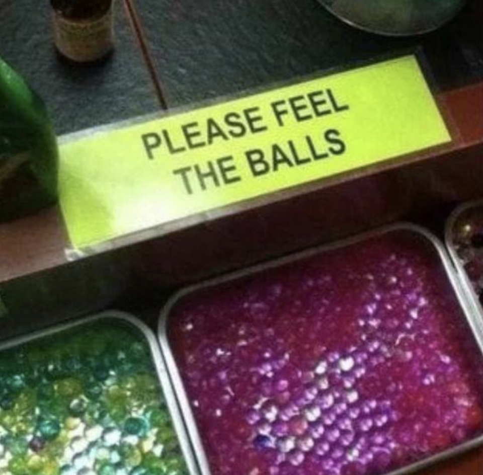 "Please feel the balls" above bins containing beads