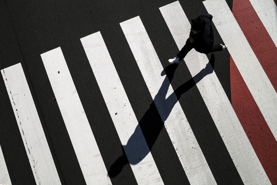 Una persona cruza una calle en Tokio, Japón, durante los días de emergencia por el coronavirus, el 26 de abril de 2021. (AP Foto/Kiichiro Sato)