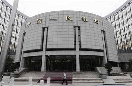 A staff member walks in front of the headquarters of the People's Bank of China (PBOC), the central bank, in Beijing, in this June 25, 2013 file photo. REUTERS/Jason Lee/Files