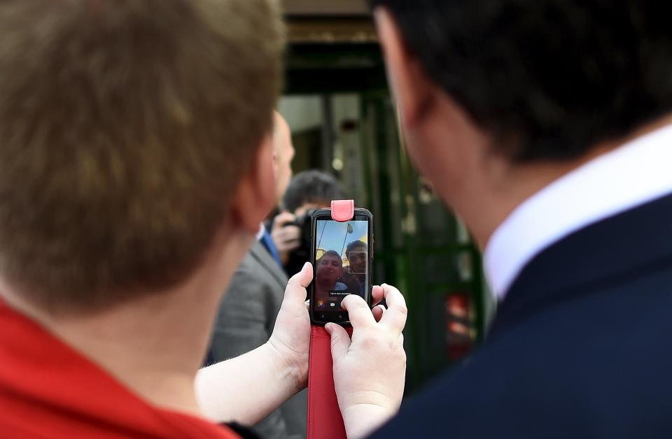 Britain's opposition Labour Party leader Ed Miliband (R) is reflected in a supporter's mobile phone as he poses for a "selfie" before the launch of their Manifesto for Young People at Bishop Grosseteste University in Lincoln, central England April 17, 2015. REUTERS/Dylan Martinez