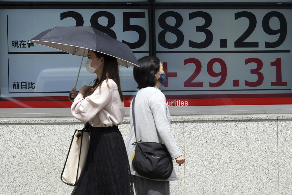 Women wearing protective masks walk in front of an electronic stock board showing Japan's Nikkei 225 index at a securities firm Wednesday, May 26, 2021, in Tokyo. Asian stock markets rose Wednesday as inflation fears eased and investors looked ahead to U.S. data that are expected to show economic growth accelerating. (AP Photo/Eugene Hoshiko)