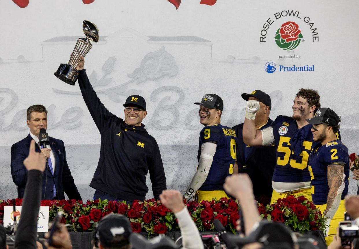 Coach Jim Harbaugh holds the Rose Bowl trophy after Michigan defeated Alabama on Jan. 1.