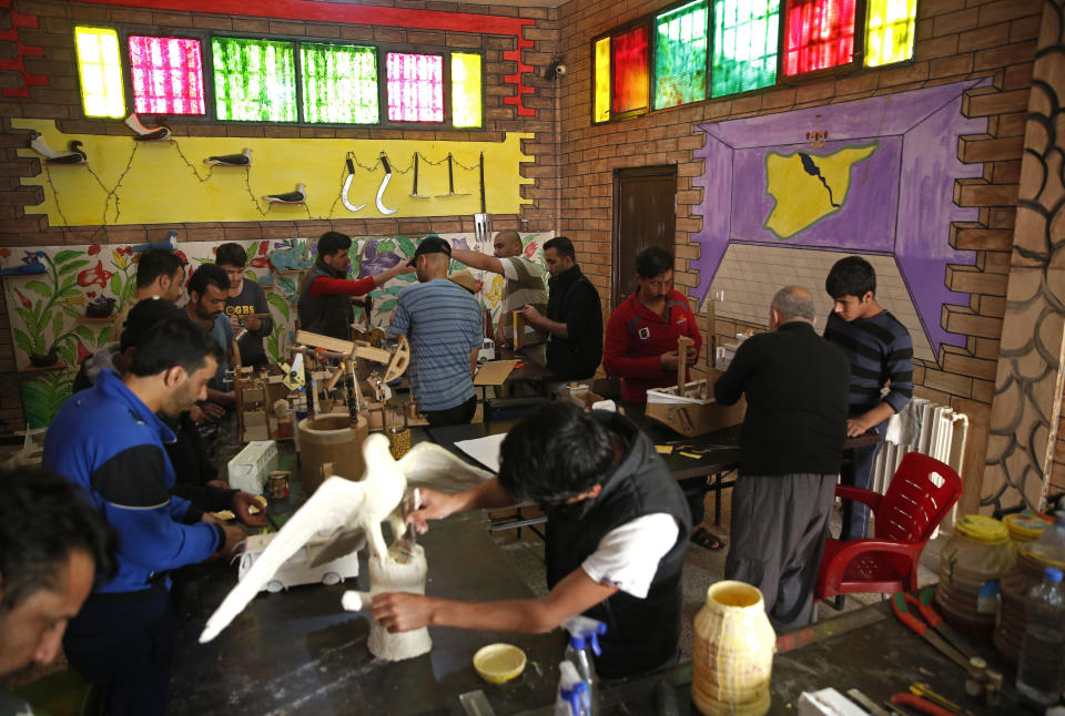 CAPTION ADDITION: ADDS DETAILS ABOUT WHICH PRISON HAD RIOTS: FILE - In this April 3, 2018, file photo, prisoners work in a handicraft workshop at a Kurdish-run prison housing former members of the Islamic State group, in Qamishli, northern Syria. A spokesman for Kurdish-led forces in northeastern Syria said Monday, March. 30, 2020, that they have put an end to riots by Islamic State militants in a prison there. The riots broke out late on Sunday in a prison in the town of Hassakeh and lasted several hours. Kurdish authorities run more than two dozen detention facilities scattered around northeastern Syria, holding about 10,000 IS fighters. (AP Photo/Hussein Malla, File)