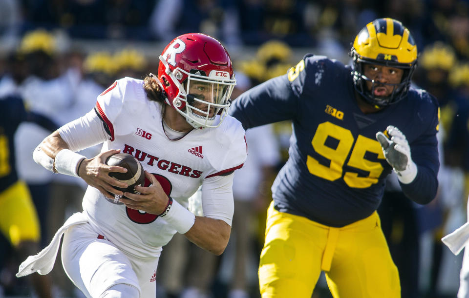 Rutgers quarterback Noah Vedral, left, scrambles away from Michigan defensive lineman Donovan Jeter (95) in the second quarter of an NCAA college football game in Ann Arbor, Mich., Saturday, Sept. 25, 2021. (AP Photo/Tony Ding)