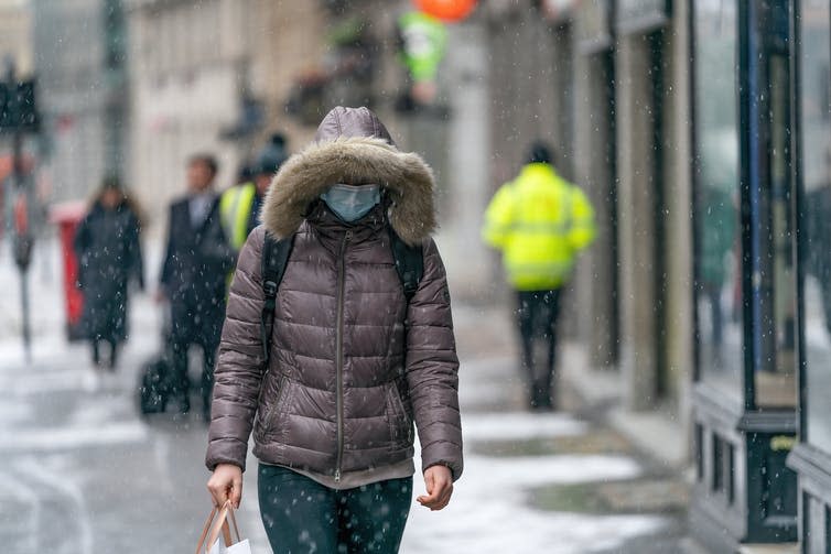 A woman walking outside in winter in a mask