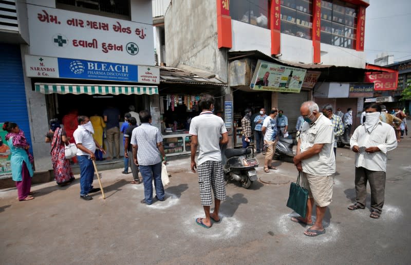 People queue standing in circles drawn with chalk to maintain safe distance as they wait to buy medicine during a 21-day nationwide lockdown to limit the spreading of coronavirus disease (COVID-19), in Ahmedabad