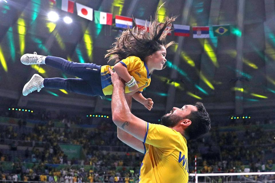 <p>William Arjona of Brazil celebrates victory over Russia with his daughter following the Men’s Volleyball Semifinal match on Day 14 of the Rio 2016 Olympic Games at the Maracanazinho on August 19, 2016 in Rio de Janeiro, Brazil. (Photo by Patrick Smith/Getty Images) </p>