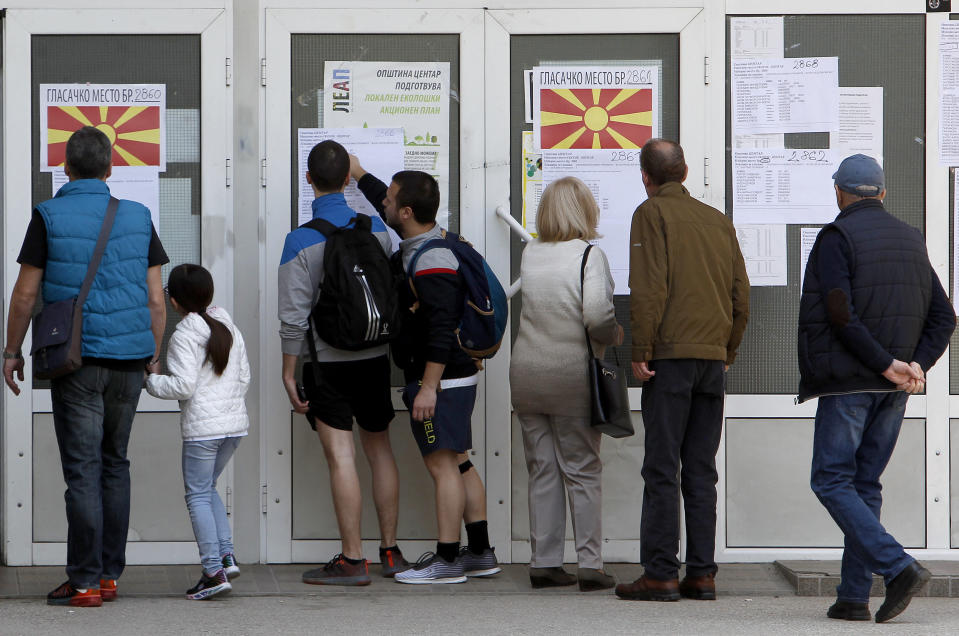 People check lists before voting in the presidential election outside a polling station in Skopje, North Macedonia, Sunday, April 21, 2019. Polls were opened early on Sunday in North Macedonia for presidential elections seen as key test of the government following deep polarization after the country changed its name to end a decades-old dispute with neighboring Greece over the use of the term "Macedonia". (AP Photo/Boris Grdanoski)