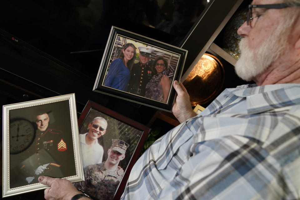 Joey Reed holds photos of his son Marine veteran and Russian prisoner Trevor Reed at his home in Fort Worth, Texas, Tuesday, Feb. 15, 2022. Russia is holding Trevor Reed, who was sentenced to nine years on charges he assaulted a police officer. (AP Photo/LM Otero)