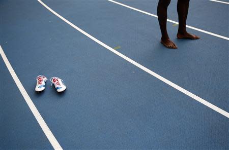 Sprinter Usain Bolt of Jamaica stands barefooted next to his track shoes after winning the men's 4x100 metres relay final during the IAAF World Athletics Championships at the Luzhniki stadium in Moscow in this August 18, 2013 file photograph. REUTERS/Kai Pfaffenbach/Files