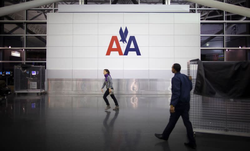 FILE PHOTO: People walk past an American Airlines logo at John F. Kennedy (JFK) airport in in New York