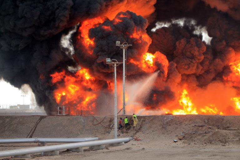 Yemeni fighters of the southern separatist movement and firefighters attempt to extinguish a blaze at an oil refinery in the port city of Aden on June 27, 2015, following shelling by Shiite Huthi rebels