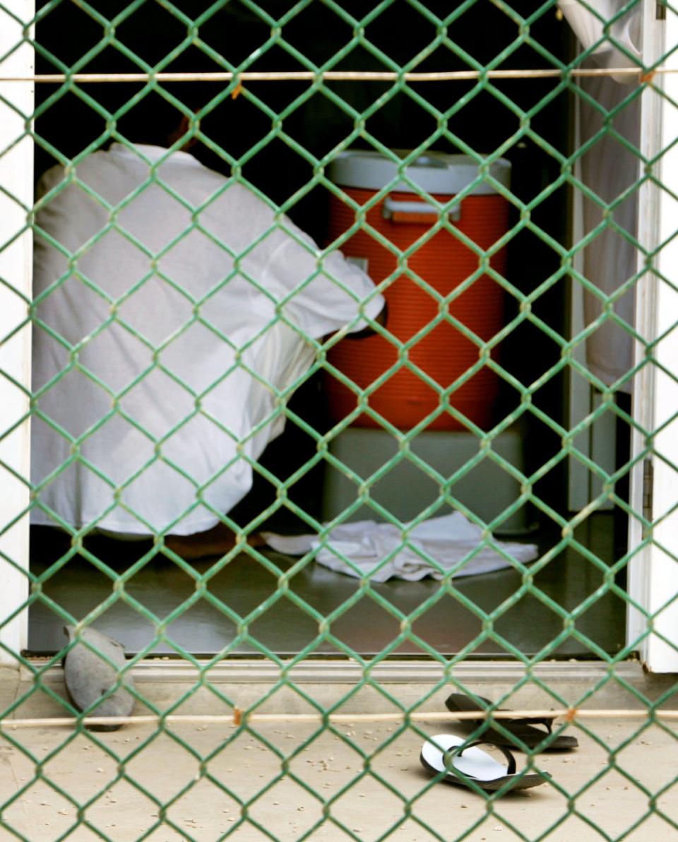 KRT WORLD NEWS STORY SLUGGED: GUANTANAMO-TRIBUNAL KRT POOL PHOTOGRAPH BY MARK WILSON/GETTY IMAGES (August 26) GUANTANAMO BAY, CUBA -- A detainee sits near a water cooler at Camp 4 inside of the maximum security prison Camp Delta at Guantanamo Naval Base in Guantanamo Bay, Cuba, on Wednesday, August 26, 2004. This week the U.S. Military held preliminary hearings for four detainee's charged with conspiracy to commit war crimes. (nk) 2004