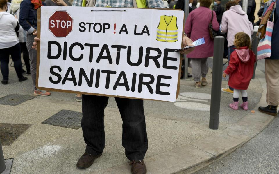 A protester holds a placard reading "Stop ! to sanitary dictatorship" during a demonstration by bar and restaurant owners in Marseille  - NICOLAS TUCAT/AFP