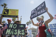 Demonstrators hold signs as they protest the lockdown and wearing masks Saturday, June 27, 2020, in Huntington Beach, Calif. (AP Photo/Marcio Jose Sanchez)