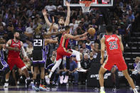 New Orleans Pelicans guard CJ McCollum (3) passes the ball as Sacramento Kings' Domantas Sabonis defends during the first half of an NBA basketball game Thursday, April 11, 2024, in Sacramento, Calif. (AP Photo/Benjamin Fanjoy)