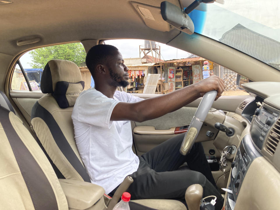 Adenekan Ayomide, 27, an undergraduate student turned a taxi driver following nationwide university strike, poses for a photograph inside his taxi in Abuja, Nigeria, Tuesday, May 10, 2022. “Nobody is talking about school again,” said Ayomide, who said he is now working more than one job and the budget he had for getting through university now looks unrealistic. (AP Photo/Chinedu Asadu)