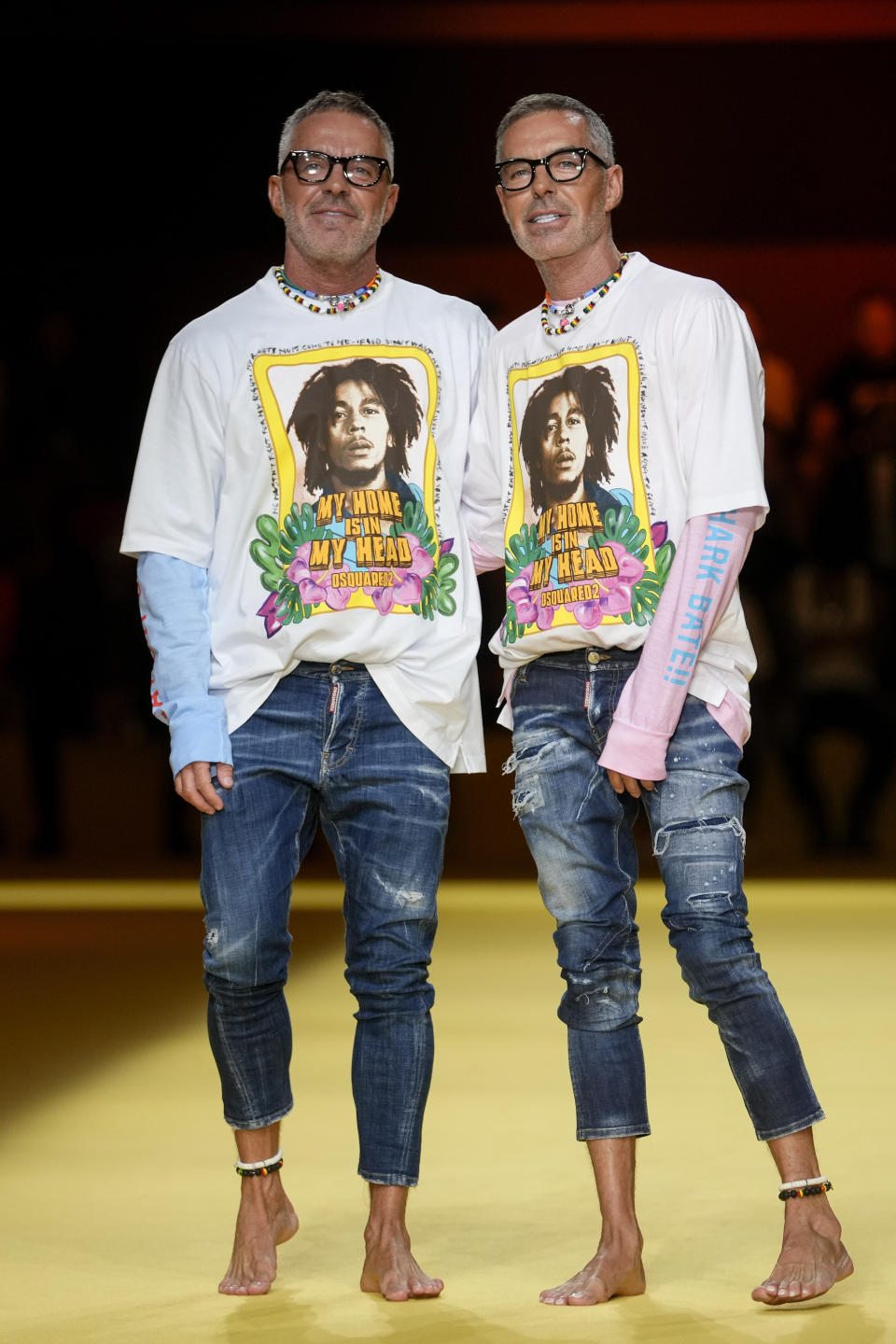 Designers Dean Caten, left, and Dan Caten accept applause at the end of the Dsquared2 men's Spring Summer 2023 collection presented in Milan, Italy, Friday, June 17, 2022. (AP Photo/Luca Bruno)