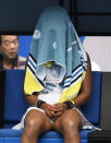 Japan's Naomi Osaka sits with a towel over her head during a break in her second round match against China's Zheng Saisai at the Australian Open tennis championship in Melbourne, Australia, Wednesday, Jan. 22, 2020. (AP Photo/Andy Brownbill)