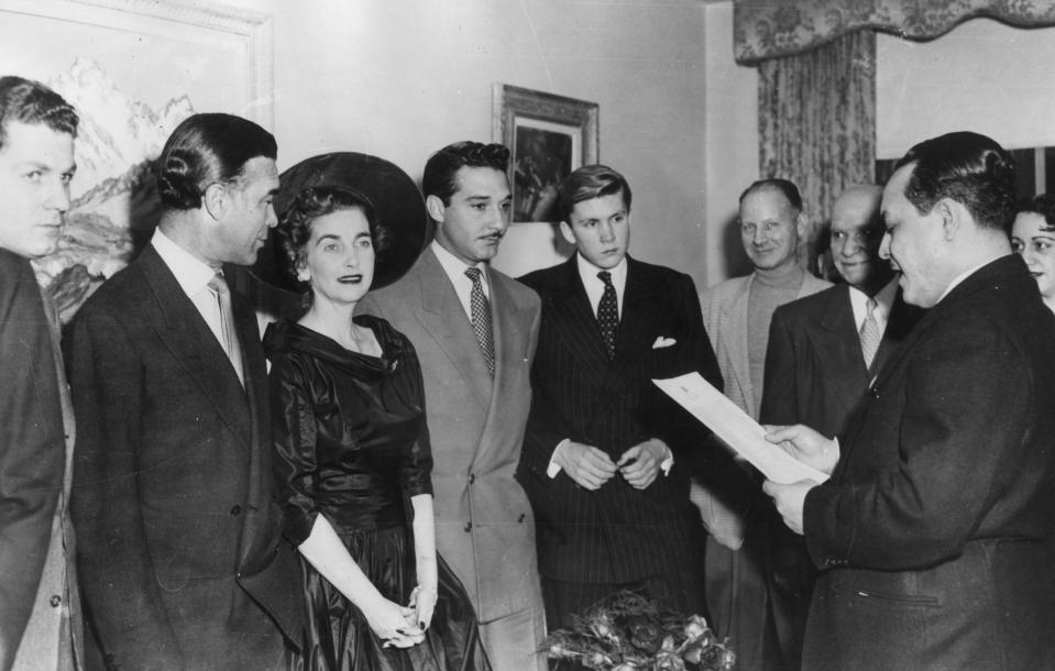 Dominican diplomat and socialite Porfirio Rubirosa (1909 - 1965) (second from left) stands next to American socialite and Woolworth's heiress Barbara Hutton (1912 - 1979) during their wedding ceremony in Paris, France, on December 30, 1953.  Hutton's teenage son Lance Haugwitz-Reventlow (1936 - 1972) (centre) is in the wedding party.  The marriage lasted just over 50 days.  (Photo: Keystone/Getty Images)