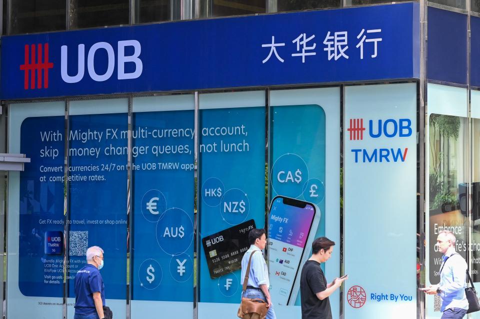 People walk in front of a branch of the United Overseas Bank (UOB) in Raffles Place. 