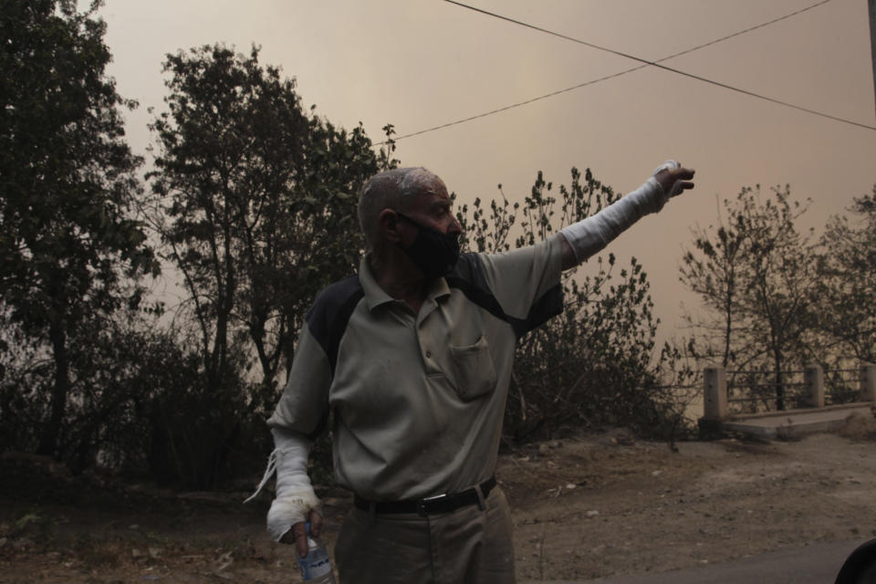 A man flees a village near Tizi Ouzou some 100 km (62 miles) east of Algiers following wildfires in this mountainous region, Tuesday, Aug.10, 2021. Firefighters were battling a rash of fires in northern Algeria that have killed at least six people in the mountainous Kabyle region, the interior minister said Tuesday, accusing "criminal hands" for some of the blazes. (AP Photo/Fateh Guidoum)