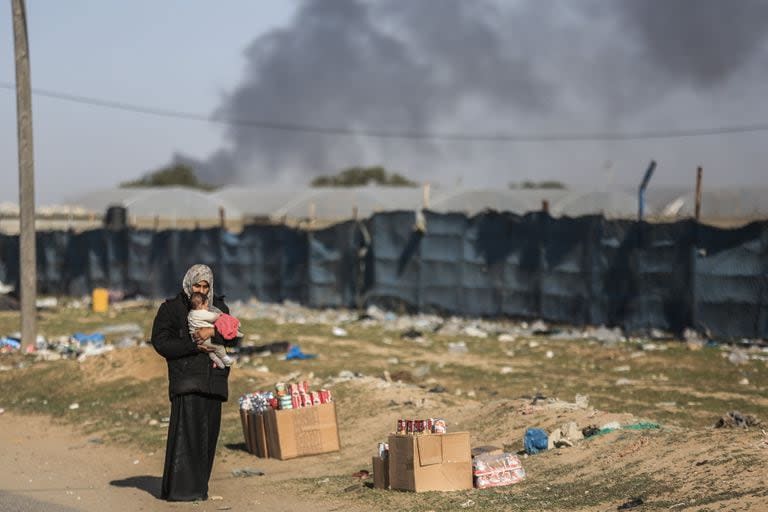 Una mujer sostiene a un niño pequeño mientras las familias palestinas huyen de la ciudad de Khan Yunis por la carretera costera que conduce a Rafah en medio del bombardeo israelí en curso.