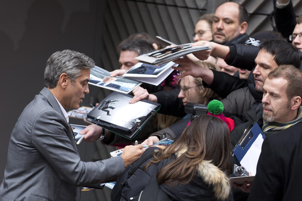 Actor George Clooney signs autographs for fans as he arrives for photo call of the film The Monuments Men during the International Film Festival Berlinale, in Berlin, Saturday, Feb. 8, 2014. (AP Photo/Axel Schmidt)