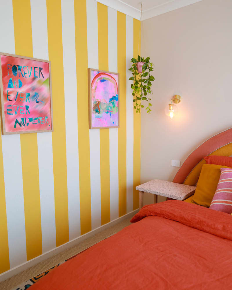 yellow and white striped wall in bedroom with orange bed