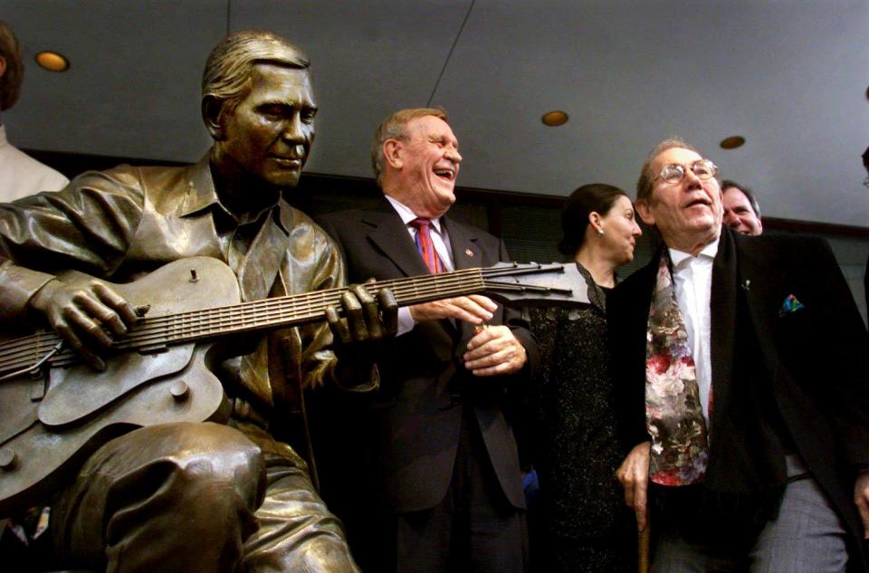 Eddy Arnold, left, laughs with Chet Atkins, right, at the dedication of a bronze statue of Atkins at the Bank of America on Fifth and Union in downtown Nashville Jan. 12, 2000.