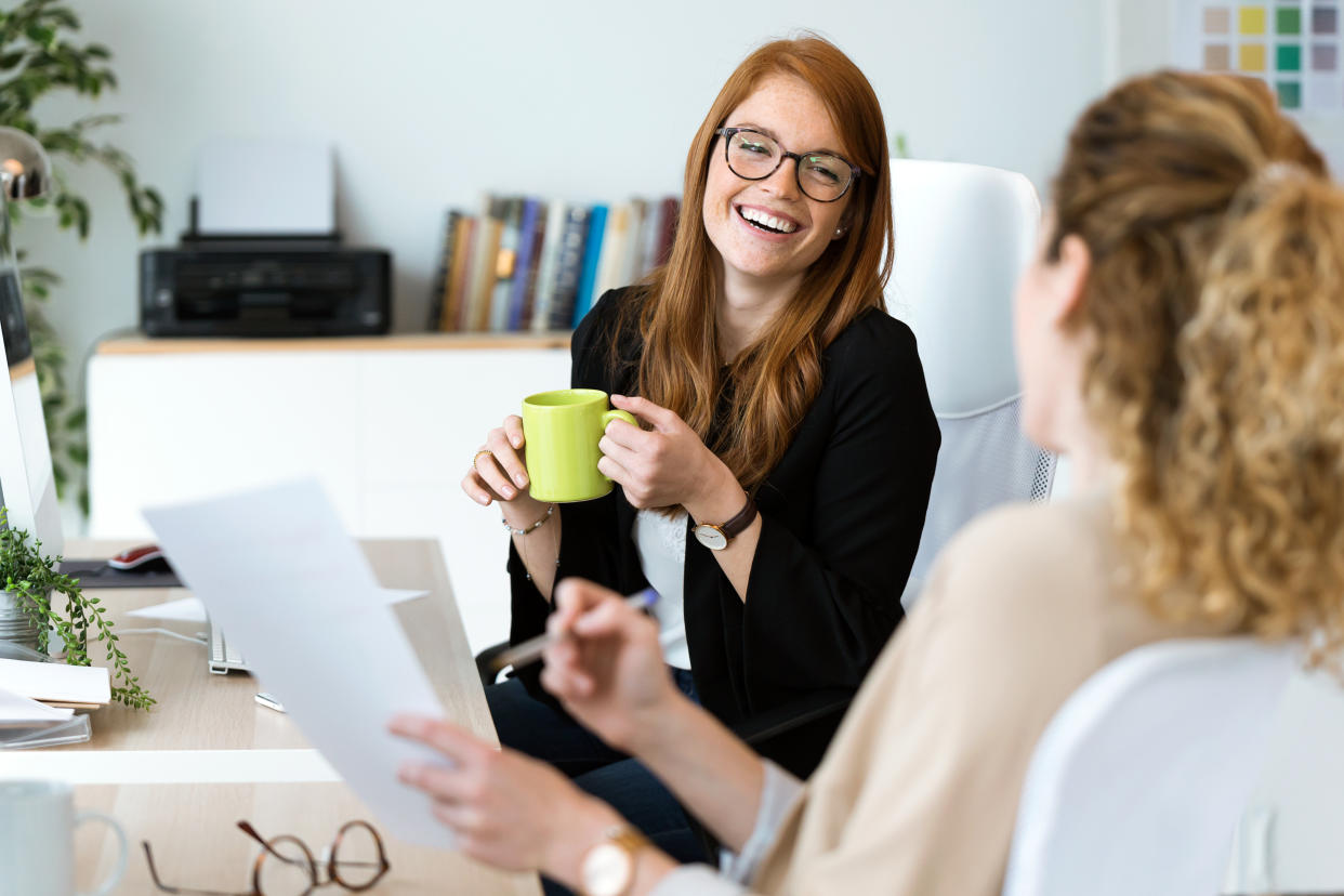 Shot of two pretty young business woman relaxing one moment while drinking coffee in the office.