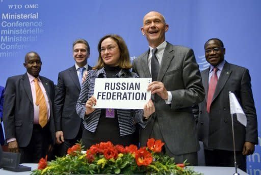 Russia's minister of economic development Elvira Nabiullina (L) and WTO Director-General Pascal Lamy (R) hold the protocol documents in front of officials during a signing ceremony on Russia accession to the World Trade Organization in Geneva, December 16