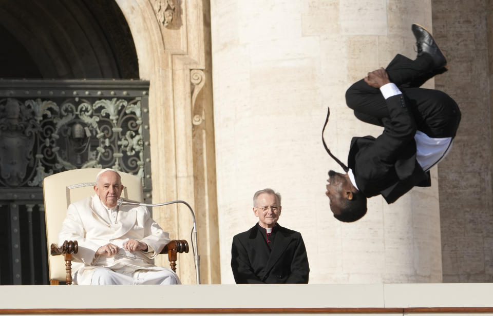 Pope Francis looks at an acrobat of the "Black Blues Brothers" performing during his weekly general audience in St. Peter's Square at The Vatican, Wednesday, Nov. 30, 2022. (AP Photo/Andrew Medichini)