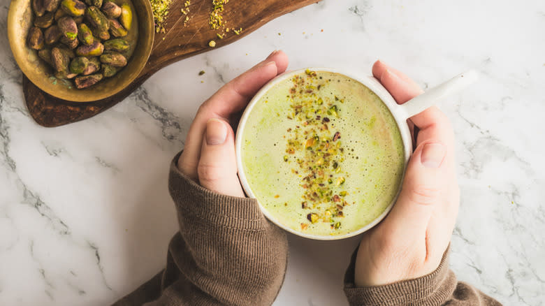 hands holding a cup of pistachio latte