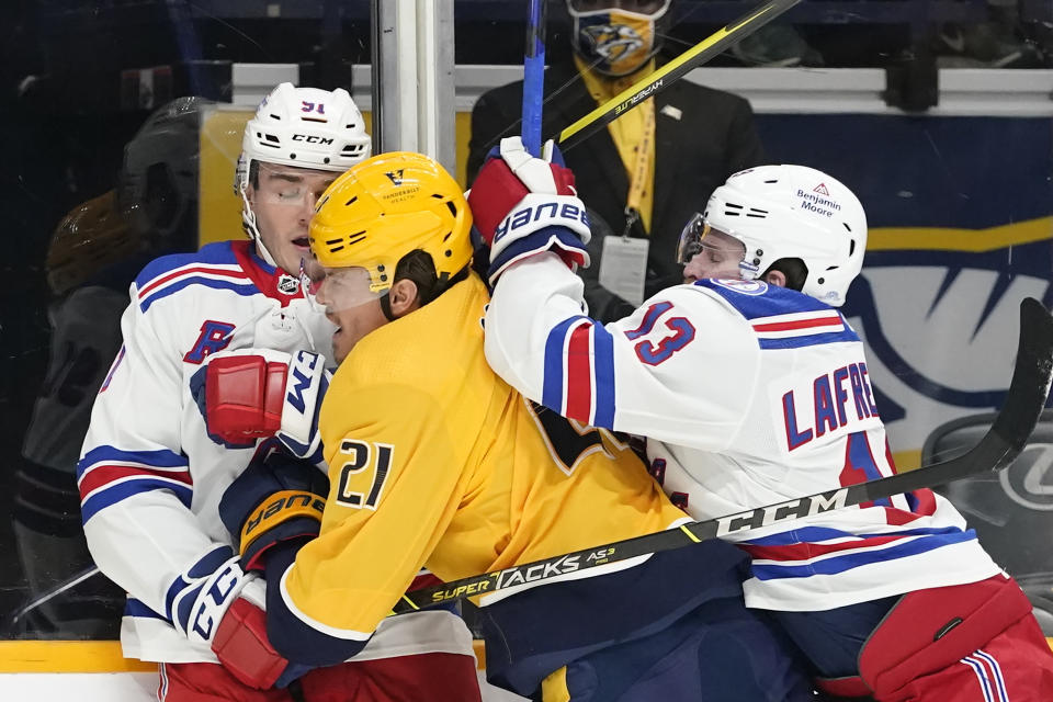 Nashville Predators center Nick Cousins (21) gets caught between New York Rangers' Sammy Blais (91) and Alexis Lafreniere (13) in the first period of an NHL hockey game Thursday, Oct. 21, 2021, in Nashville, Tenn. (AP Photo/Mark Humphrey)