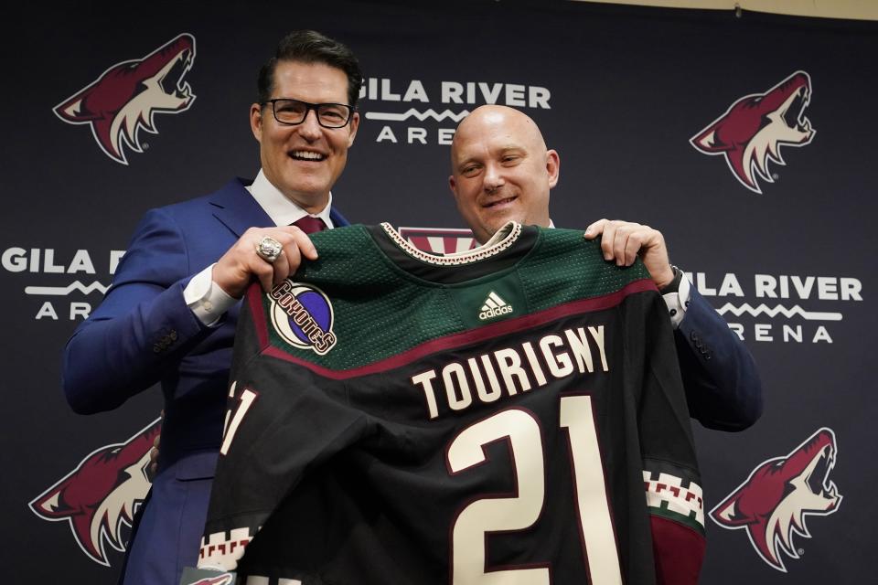 Arizona Coyotes hockey team General Manager Bill Armstrong, left, poses with new head coach Andre Tourigny, right, as the two hold up a jersey during a news conference at Gila River Arena Thursday, July 1, 2021, in Glendale, Ariz. (AP Photo/Ross D. Franklin)